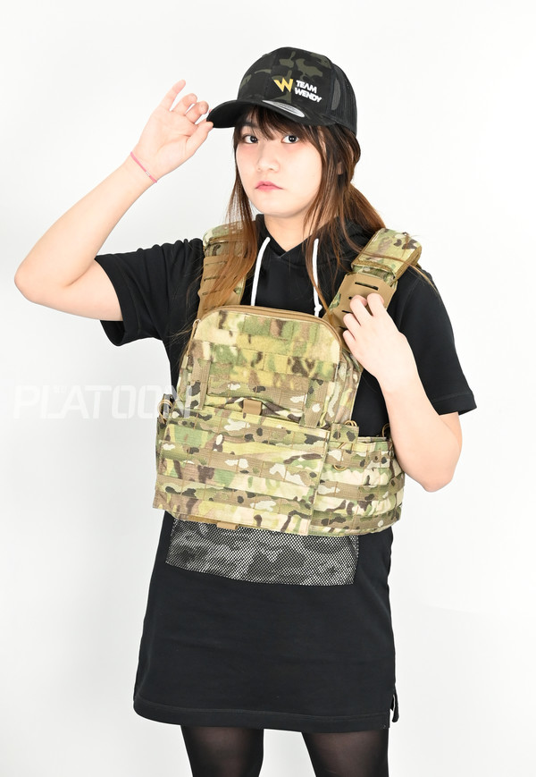 [T3 Gear] 토마호크 2 플레이트 캐리어로, 어깨 끈 부분이 다르고 앞 부분에 추가된 주머니 등에서 차이를 보인다. 역시 [Team Wendy] 모자를 착용하고 있다.