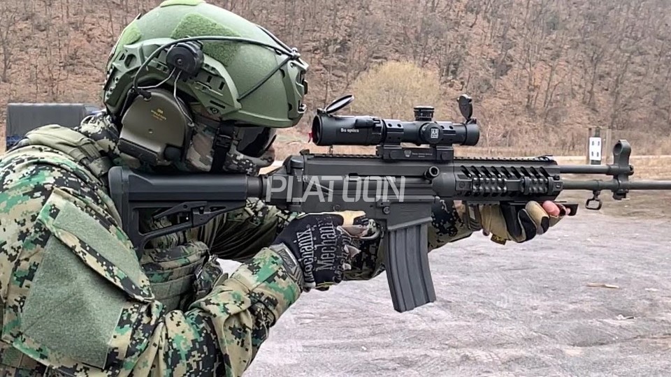 지정사수용 스코프와 앵글 그립을 장착하고 사격 중인 특전사 대원. 방열 덮개 대신 조각 레일로 사이드를 채워놨다. 해당 대원은 낮은 스코프 마운트와의 간섭을 피해 레일 장착형 가늠자를 아예 탈착시켰다. 